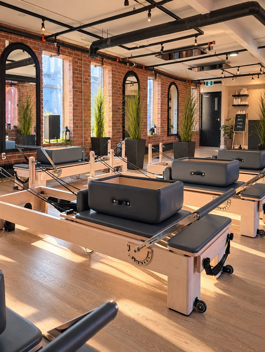 Reformer Pilates machines in the sunlit brick-walled Live Well studio